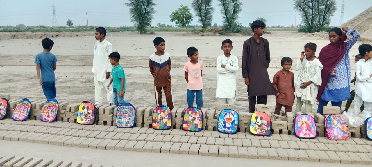 Children lined up with new school backpacks at a brick kiln